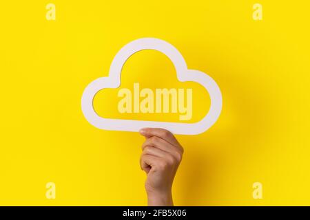 Cloud computing concept, hand holding cloud over yellow background, cloud storage Stock Photo
