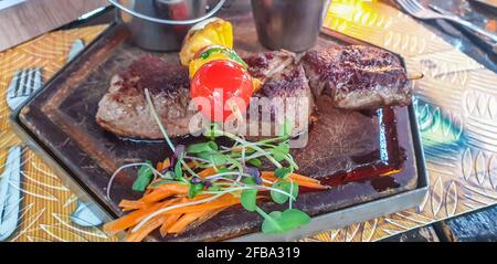 Namibian braai, Kudu, Springbok, Zebra steak with salad at a Restaurant in Windhoek, close up with selected focus Stock Photo