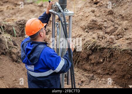 a man working in uniform is engaged in repairing the gas pipe, repairing the equipment with tools, iron communications repair gasman, improving their Stock Photo