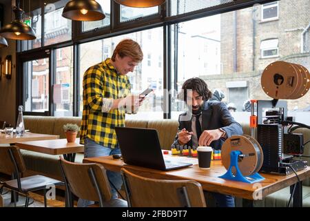 Male entrepreneurs discussing over 3D printing game while working at office Stock Photo