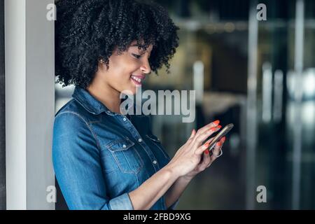 Smiling female entrepreneur using smart phone at office Stock Photo