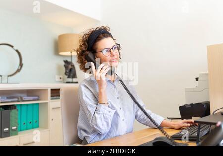 Receptionist talking on telephone at desk in hotel Stock Photo