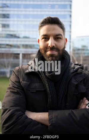 Bearded man with arms crossed standing against building Stock Photo