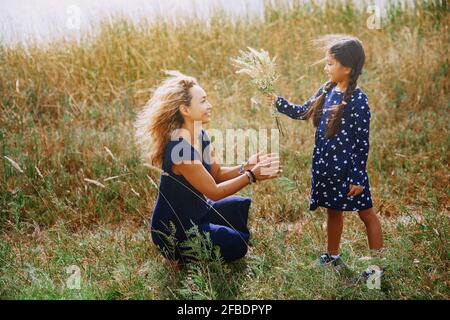 Daughter giving bunch of wildflowers to mother Stock Photo