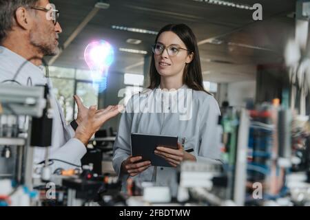Male engineer discussing with female colleague in industry Stock Photo