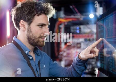 Male IT professional touching computer screen in data center Stock Photo