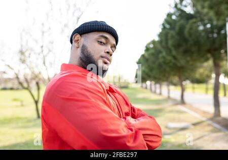 Handsome man with arms crossed standing in park Stock Photo