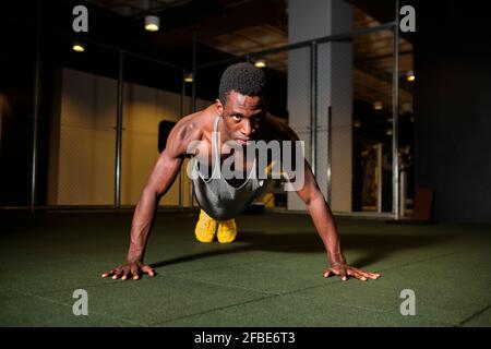 Athletic man doing push-ups exercise at gym Stock Photo