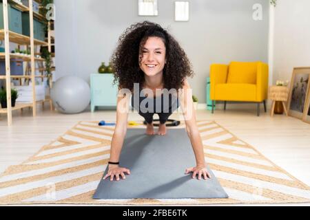Smiling beautiful woman doing push-ups at home Stock Photo