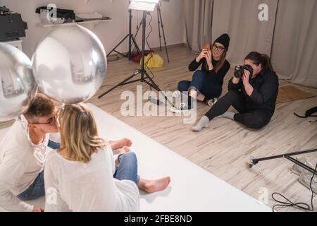 Female photographers taking pictures of couple in studio Stock Photo