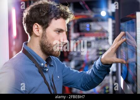 Male IT technician looking at computer screen in data center Stock Photo