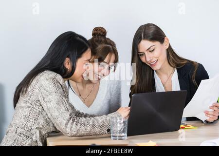 Smiling female entrepreneurs team working on laptop at office Stock Photo
