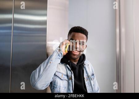 Cheerful young man talking on smart phone while looking away Stock Photo