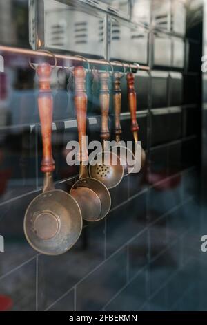 Several kitchen utensils hanging on a wall seen through glass in restaurant Stock Photo