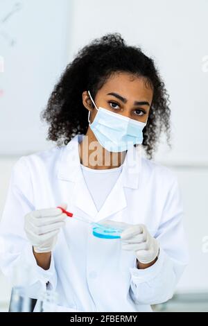 Female researcher in protective face mask working in laboratory Stock Photo