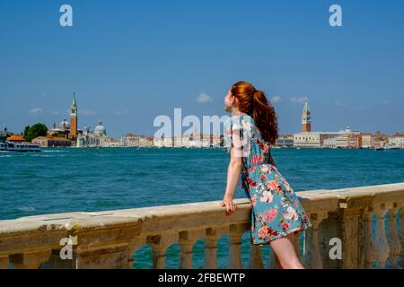 Young woman leaning on baluster during sunny day Stock Photo