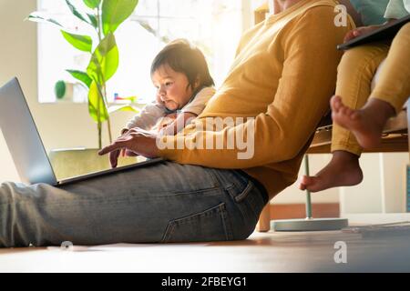 Father working on laptop while siting by daughters in home office Stock Photo