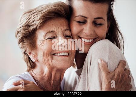 Happy young woman and grandmother hugging each other at home Stock Photo