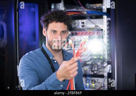 Male IT specialist looking at patch cord cables in server room Stock Photo