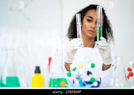 Young female researcher analyzing test tubes in laboratory Stock Photo