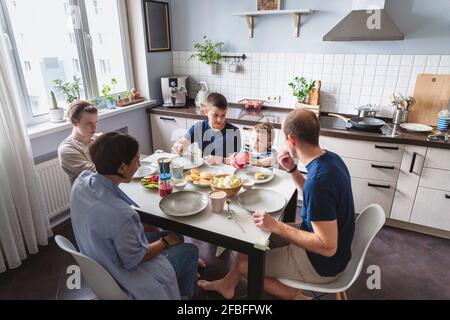 Happy family eating at dining table in kitchen at home Stock Photo