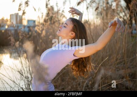 Beautiful young woman with arms raised dancing in nature Stock Photo
