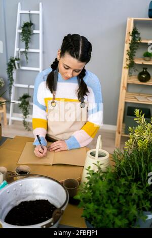 Young woman writing in book while working in workshop Stock Photo
