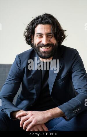 Bearded man smiling while sitting on sofa Stock Photo