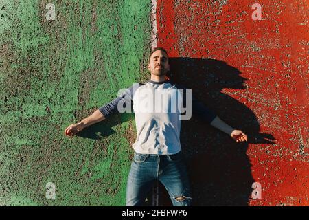 Relaxed man lying down on sports court during sunny day Stock Photo