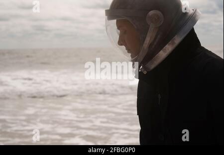 Astronautic man in space helmet at beach Stock Photo