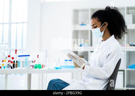 Female researcher working on digital tablet while siting on chair in laboratory Stock Photo