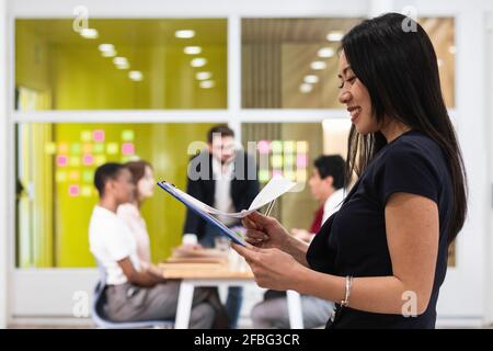 Smiling businesswoman checking documents in office Stock Photo