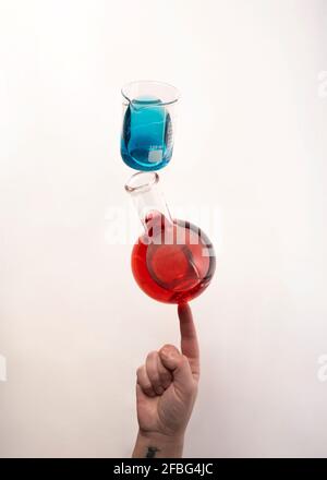 Flat bottom flask and a Berzelius beaker glass balanced on top of fingertip Stock Photo