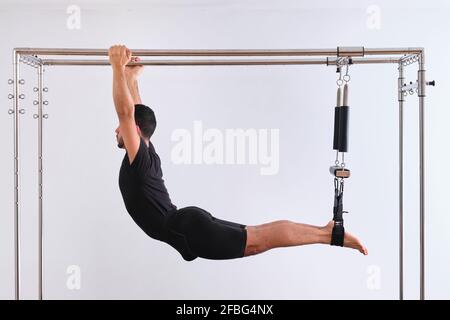 Man practicing pilates on trapeze table in exercise room stock photo
