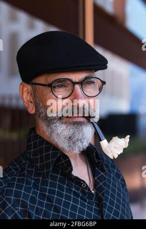 Bearded mature man with smoking pipe looking away Stock Photo