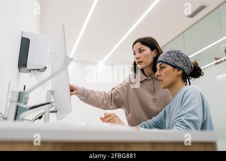 Dentist using computer while working with colleague at office Stock Photo