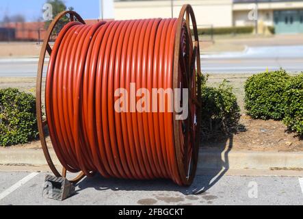 Huge roll of orange cable for underground cable installation sitting along a street Stock Photo