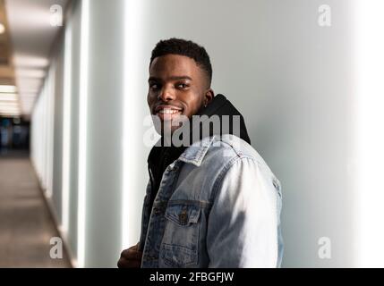 Young man wearing denim jacket in corridor Stock Photo