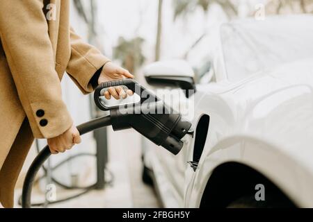 Woman charging electric car at station Stock Photo