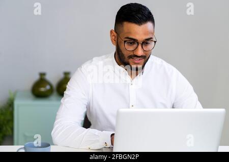 Young businessman with eyeglasses working on laptop at office Stock Photo