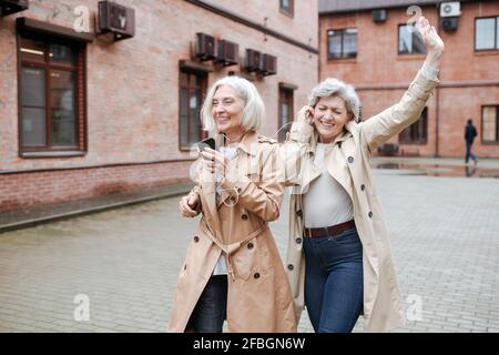 Happy female friends sharing headphones while listening music and dancing Stock Photo