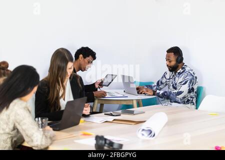 Businessmen working while sitting with colleagues in creative office Stock Photo