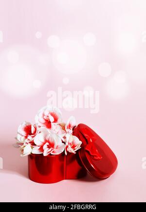 Heart shape red gift box and bouquet on pink background. Stock Photo