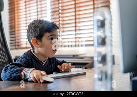 Curious boy using computer at home Stock Photo