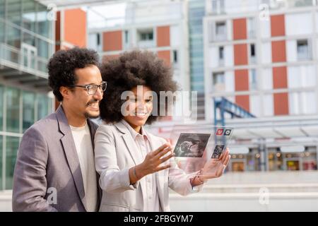 Business couple using futuristic transparent glass digital tablet in city Stock Photo