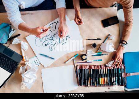 Young multi ethnic couple working together on calligraphy writing at studio Stock Photo