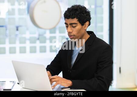 Young man working on laptop at creative office Stock Photo
