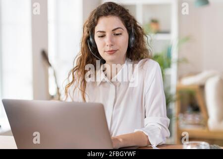 Beautiful female customer service representative using laptop at home office Stock Photo
