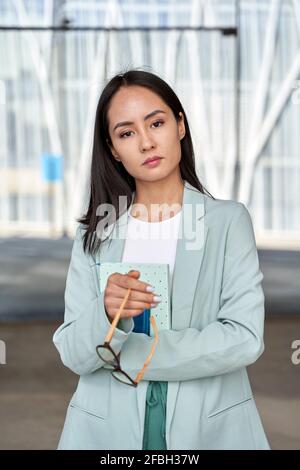 Businesswoman wearing blazer holding dairy and eyeglasses Stock Photo