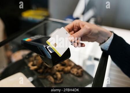 Female customer making payment through credit card in illuminated restaurant Stock Photo